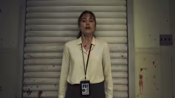 Agent Lee Harker stands before a closed shutter with blood on her neck