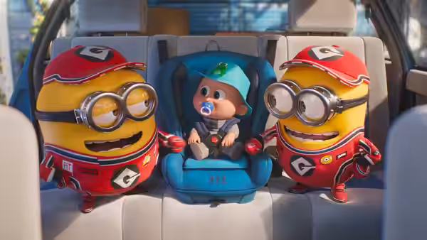 Two minions sit beside a baby in a car seat
