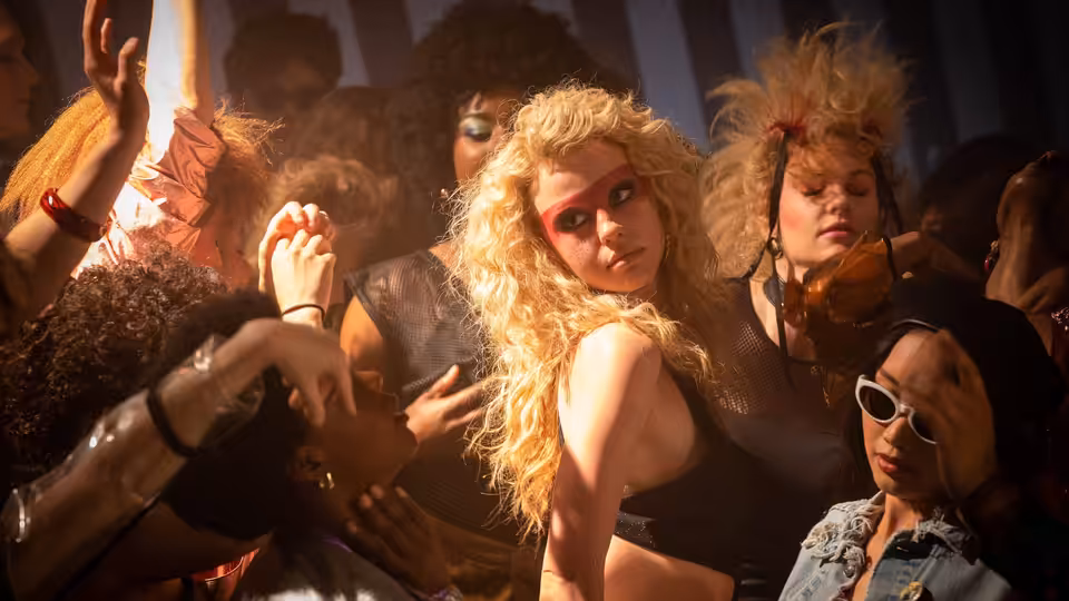 Maxine Minx (Mia Goth) dancing among a crowd in a nightclub