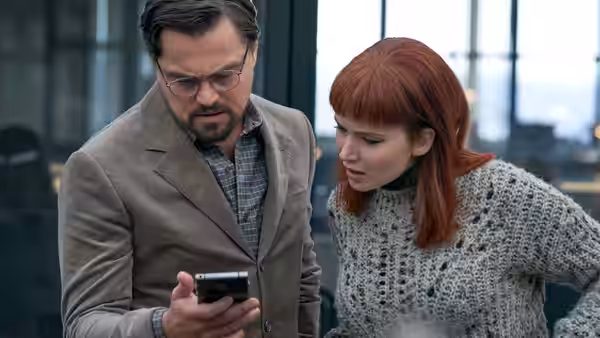 Dr. Randall Mindy (Leonardo DiCaprio) and Kate Dibiasky (Jennifer Lawrence) check a smartphone together