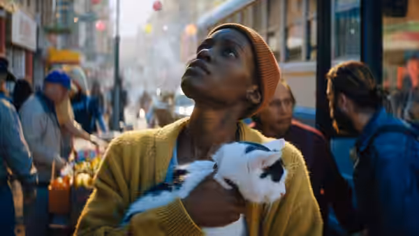Samira (Lupita Nyong'o) clutches a cat while looking up on a busy street