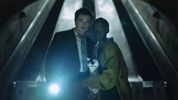 Samira (Lupita Nyong'o) and Eric (Joseph Quinn) shelter with a cat beneath a metal structure