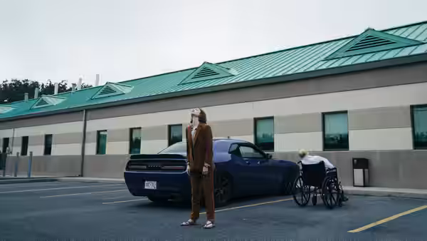 A woman standing in a parking lot beside a person in a wheelchair
