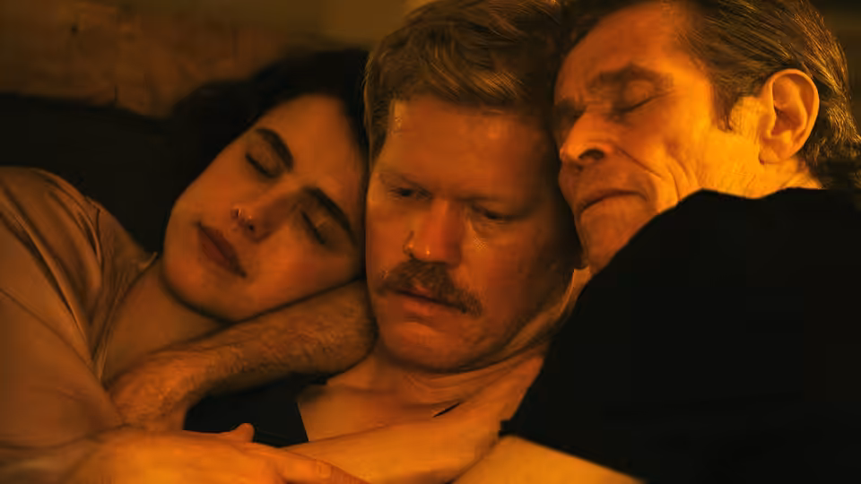 Three adults lying together in bed with their eyes closed