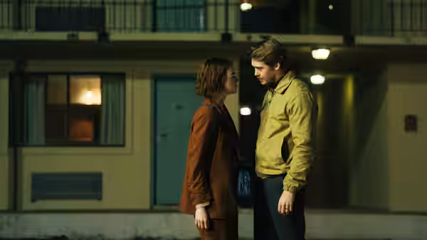A woman and a man standing face to face outside a building at night