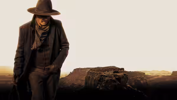 A man in a dark coat and hat walks through a rugged desert landscape at dusk