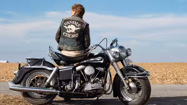 a man in a Vandals Chicago jacket sitting on a motorcycle