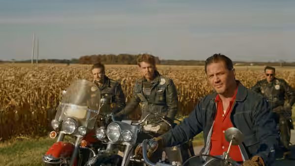 Zipco (Michael Shannon) riding a motorcycle through a wheat field with others