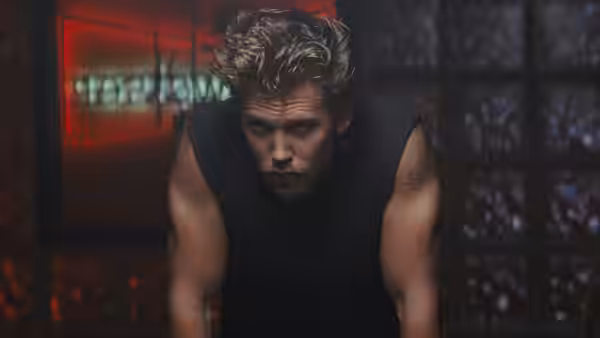 Benny (Austin Butler) leaning forward in a black tank top indoors