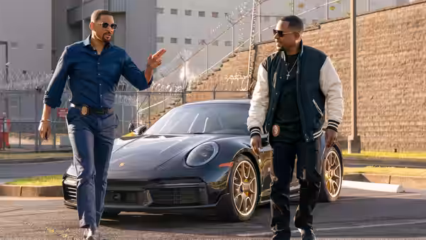 Mike Lowrey (Will Smith) gesturing to Marcus Burnett (Martin Lawrence) beside a sports car