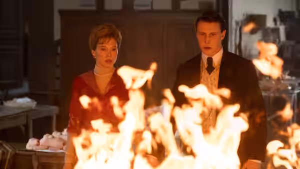 Gabrielle (Léa Seydoux) and Louis (George MacKay) facing a large open fire indoors