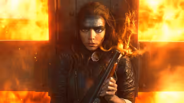 Furiosa (Anya Taylor-Joy) holding a shotgun before a burning wooden wall