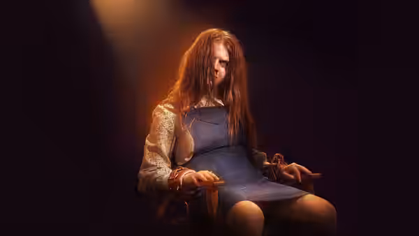 Lilly D'Abo (Ingrid Torelli) sits bound in a chair with eyes closed under a spotlight