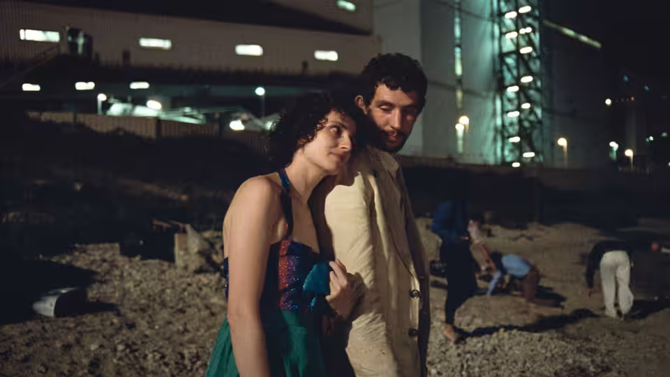 Arthur (Josh O'Connor) standing close with a woman on rocky ground at night