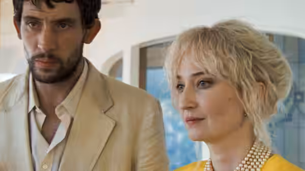 Arthur (Josh O'Connor) next to a blonde woman in a yellow top