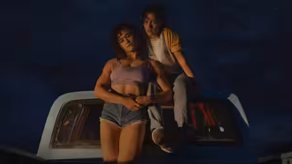 Jackie (Katy O'Brian) and Lou (Kristen Stewart) sitting together on a pickup truck at night