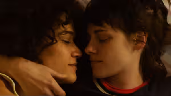Jackie (Katy O'Brian) and Lou (Kristen Stewart) embracing face to face with eyes closed