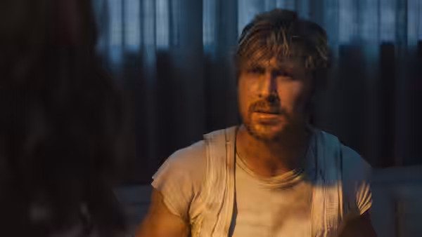 Colt Seavers (Ryan Gosling) sits facing a woman in a dimly lit room