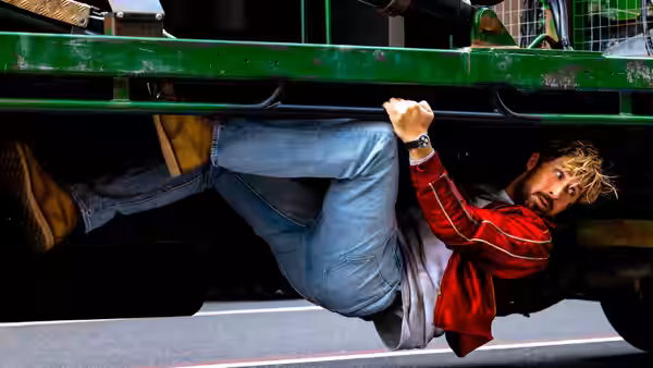 Colt Seavers (Ryan Gosling) clings underneath a speeding green truck on the road