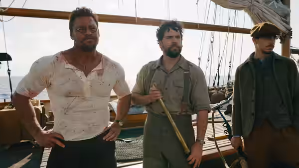 Henry Cavill stands with two men on a ship's deck at sea