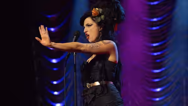 Amy (Marisa Abela) singing on stage with arm extended outward