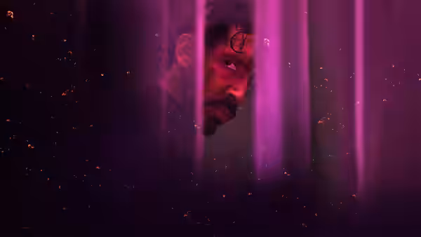 Kid (Dev Patel) looks through vertical bars under purple light