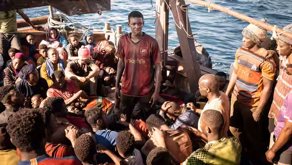 crowded migrants on a wooden boat at sea in daylight