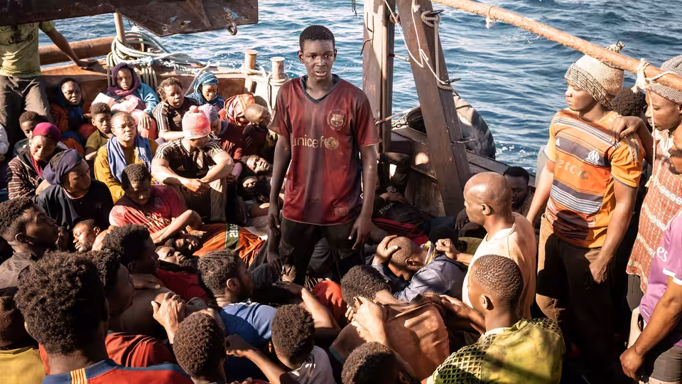 crowded migrants on a wooden boat at sea in daylight