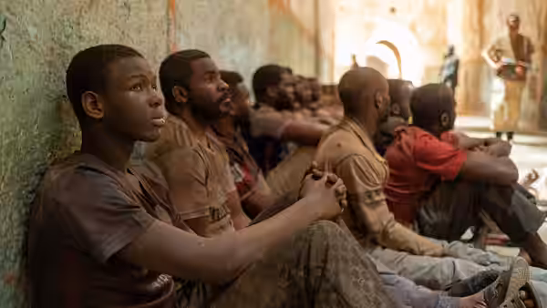 young men sitting along a wall in a corridor