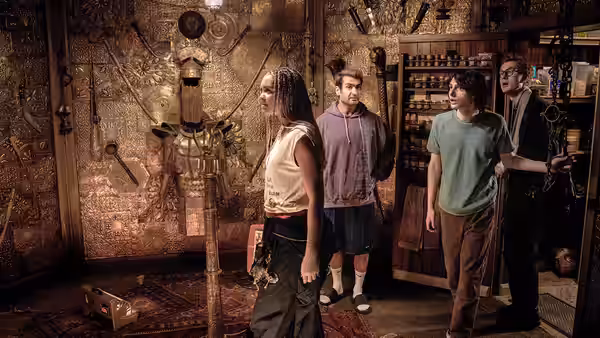 Four people stand among shelves of occult artifacts and proton pack equipment