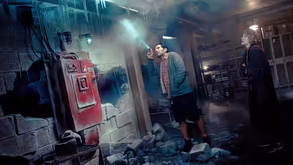 Gary Grooberson (Paul Rudd) shines a flashlight at a damaged wall as Callie Spengler watches