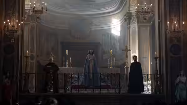 A robed figure stands at the altar of a grand church with clergy and candles nearby