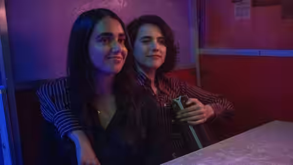 Marian and Jamie sitting close together in a dimly lit booth
