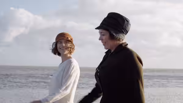 Rose Gooding (Jessie Buckley) smiling beside Edith Swan (Olivia Colman) on a windy beach