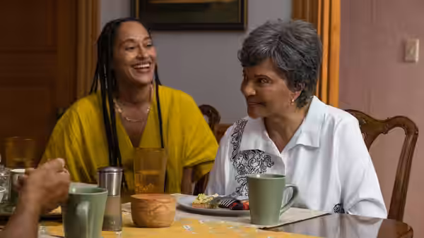 Agnes Ellison (Leslie Uggams) talking with a woman at a dining table