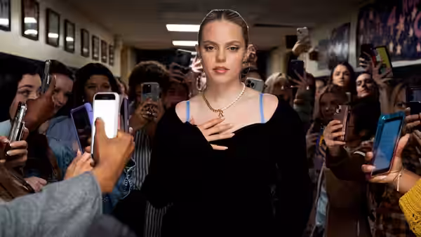 Regina George (Reneé Rapp) walks a school hallway surrounded by students with phones