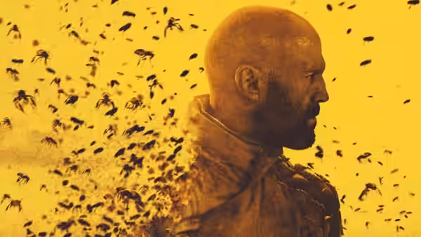 Adam Clay (Jason Statham) in profile amid a swarm of bees in yellow light
