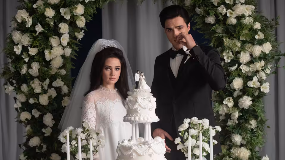 Priscilla (Cailee Spaeny) and Elvis (Jacob Elordi) beside a tiered wedding cake