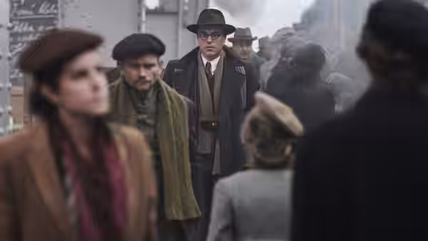 Young Nicholas Winton (Johnny Flynn) standing among a crowd at a station