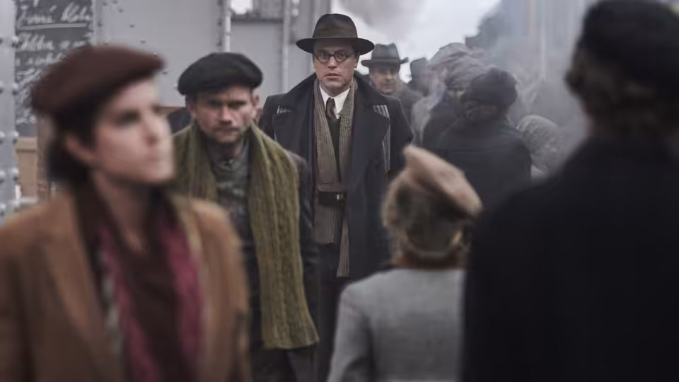 Young Nicholas Winton (Johnny Flynn) standing among a crowd at a station