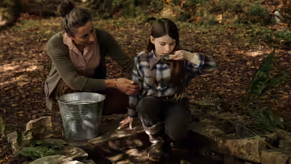 Eibhlín (Carrie Crowley) watches Cáit (Catherine Clinch) drink from a stream in the woods