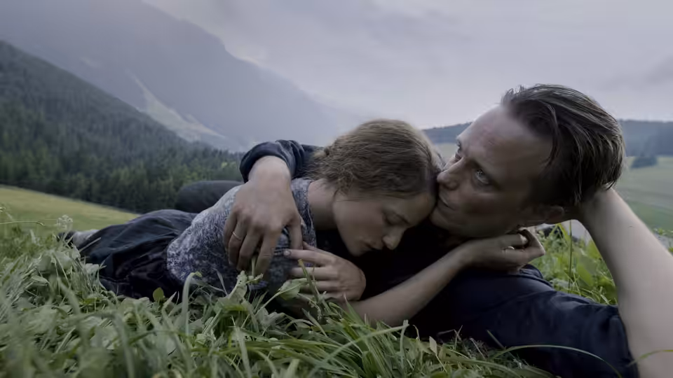 Franz Jägerstätter (August Diehl) and Fani Jägerstätter (Valerie Pachner) embracing in a grassy meadow