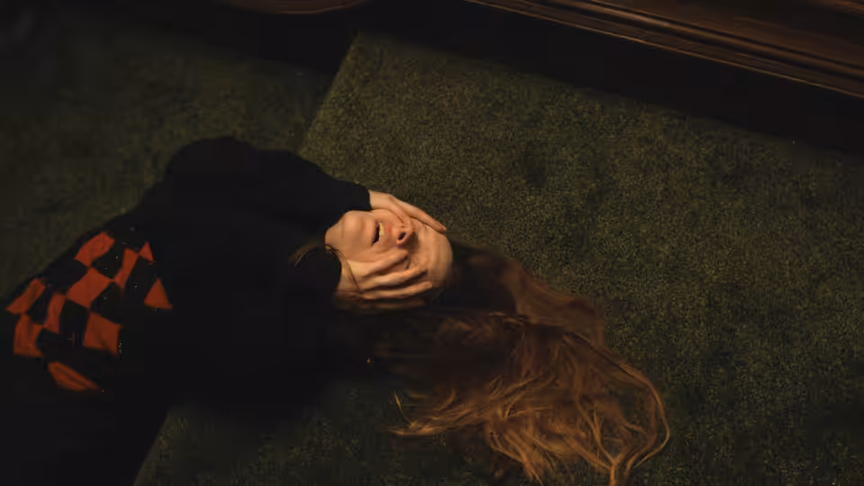 Maud (Morfydd Clark) lies on the floor with her hands covering her face