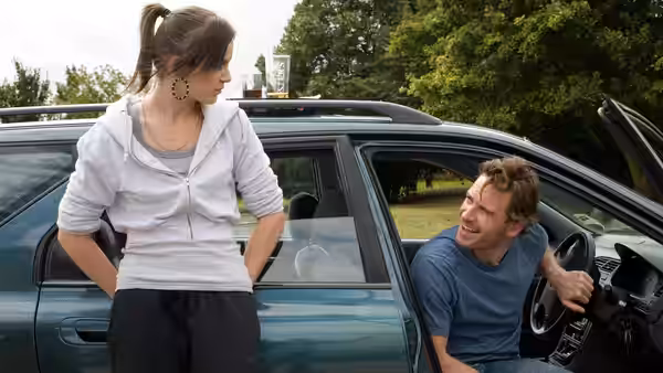 Mia (Katie Jarvis) talking to Connor (Michael Fassbender) by a car