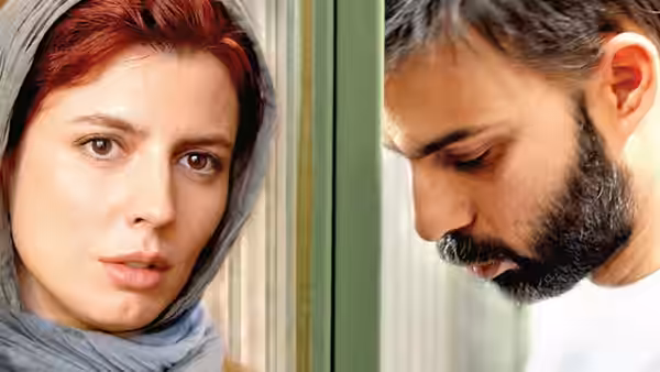 A woman in a gray headscarf looks forward beside a bearded man looking down