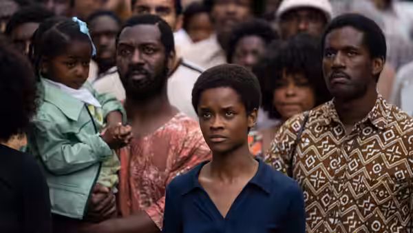Woman standing among a crowd of people looking forward intently