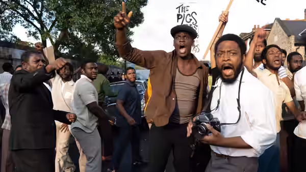 Men shouting and raising fists during a protest on a city street