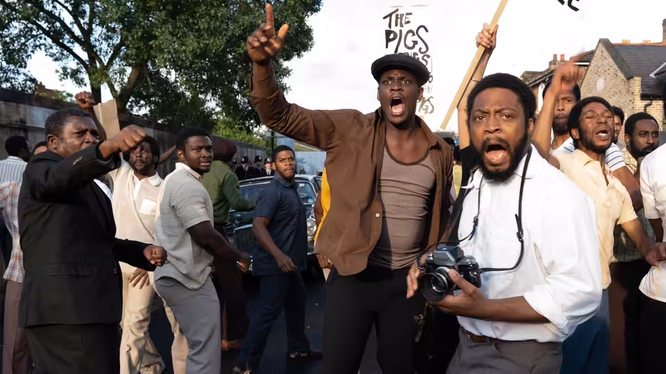 Men shouting and raising fists during a protest on a city street