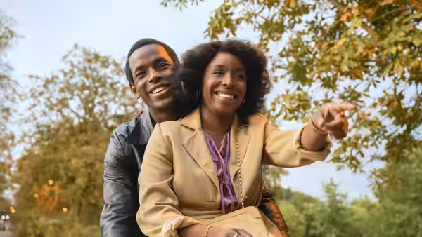 Couple smiling and pointing while standing outdoors among trees