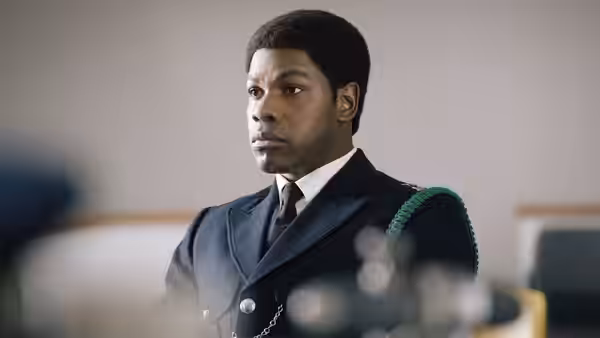 Man in dark police uniform looking to the side indoors